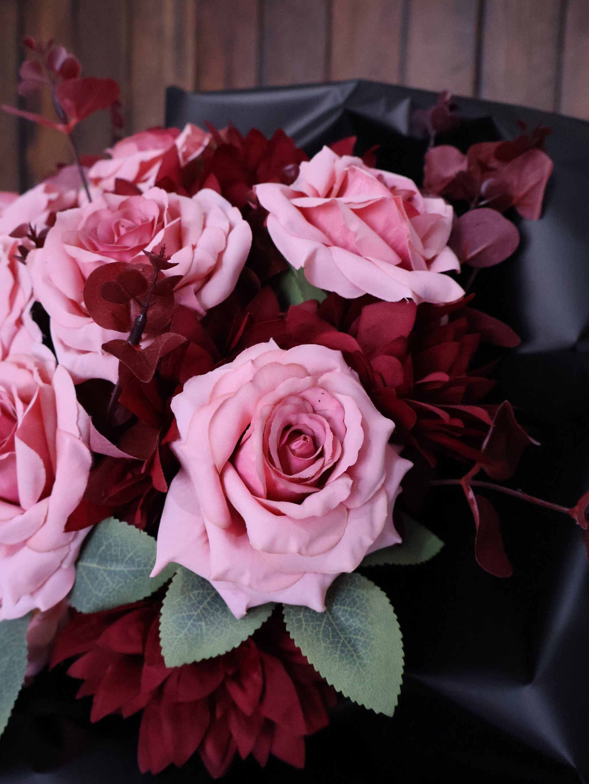 Pembe güller ve kırmızı yapraklarla hazırlanmış siyah kağıt buket – Mert’s Flora